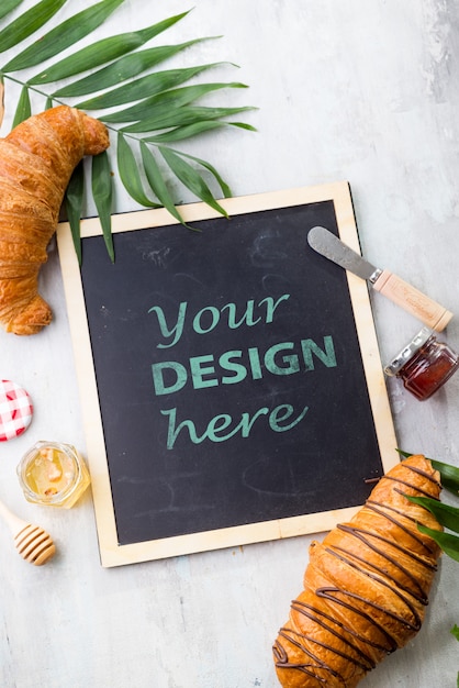 Croissant and jam with leaves palm, chalk board  flat lay mockup