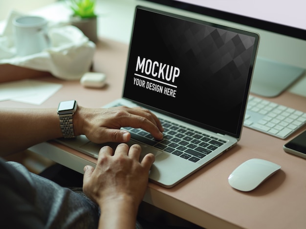 Cropped shot of male hands typing on mockup laptop