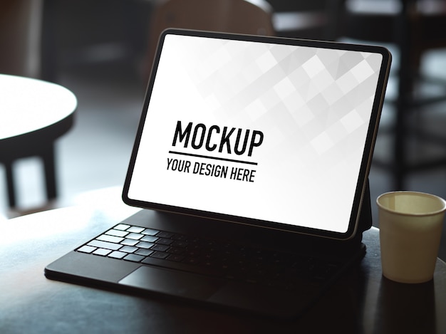 Cropped shot of mock up digital tablet with keyboard and paper cup on coffee table