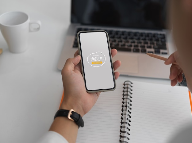 작업 공간에서 스마트 폰을 모의에서 정보를 찾는 사업가의 자른 샷
