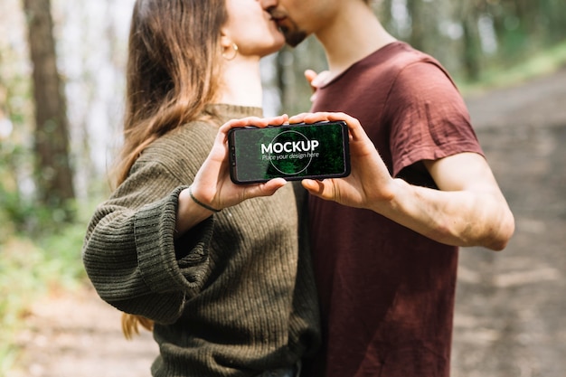 PSD cute couple in nature with smartphone mock-up