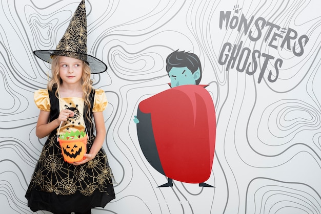 Cute girl dressed as a witch standing nearby an animated vampire