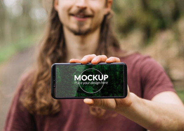 Uomo carino in natura con smartphone mock-up