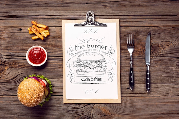 Cutlery and burger with fries menu on wooden background