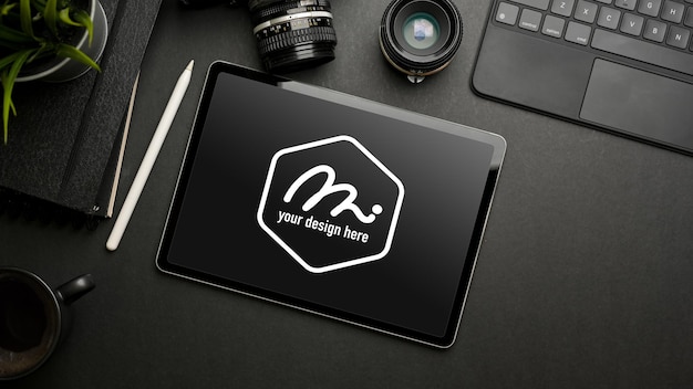 Dark creative flat lay with digital tablet mockup, camera, stationery and accessories, top view