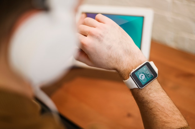 PSD uomo defocused che lavora da casa mentre guardando smartwatch