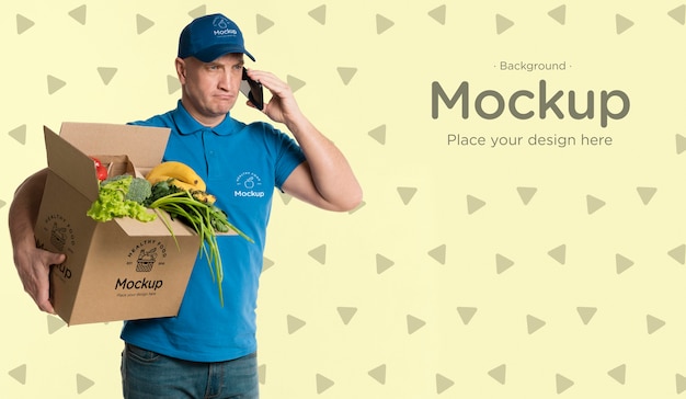 Delivery man holding a box with vegetables mock-up