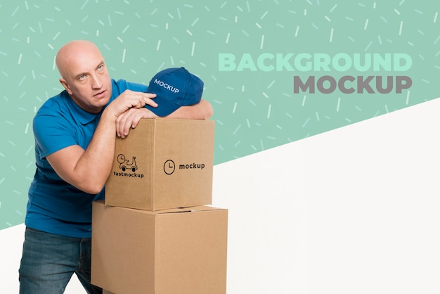 delivery man looking tired next to a bunch of boxes