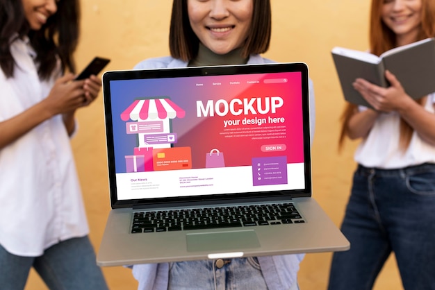 Different beautiful women holding a laptop mock-up