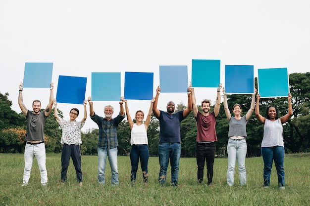 Diverse people holding blue squared boards in the park