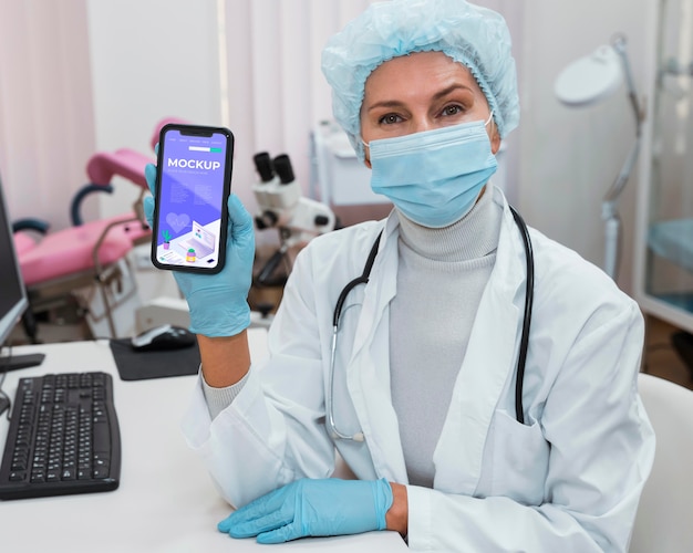 Doctor holding phone mock-up at desk