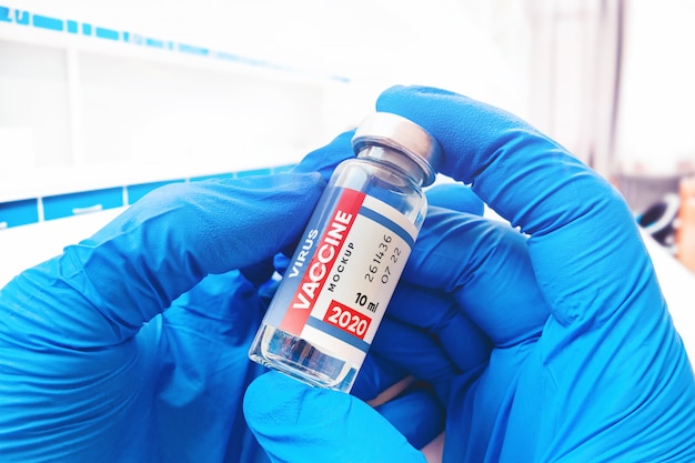 Doctor in medical gloves holds a vaccine bottle mockup