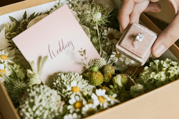 Doos gevuld met verschillende bloemen en een trouwring