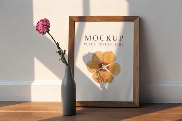 Dried pink peony flower in a gray vase by a wooden frame mockup on the floor