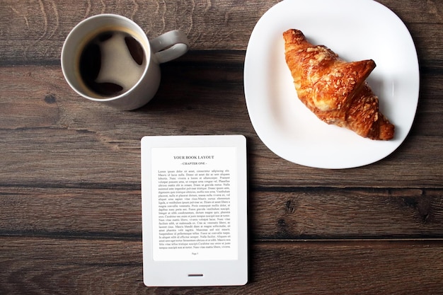 E-book reader mock-up, colazione con croissant su un piatto bianco e caffè