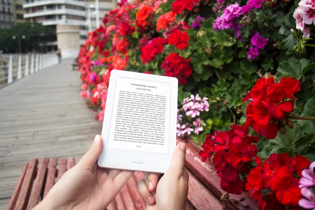 PSD e-book reader, mock-up, reading on the bench, flowers background