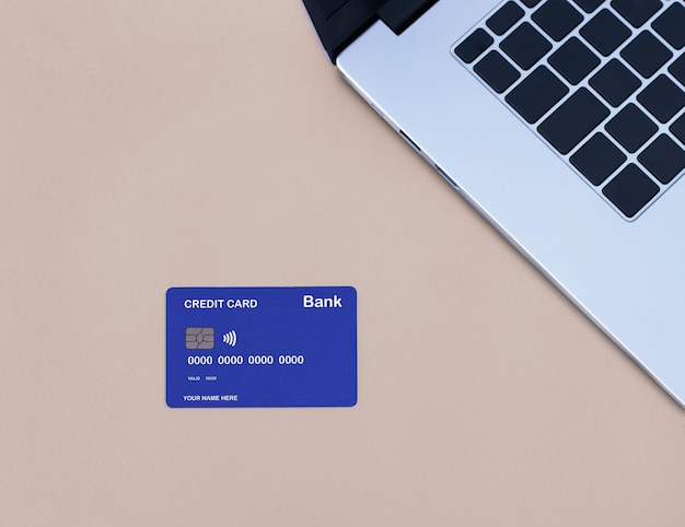 Een blauw-witte creditcard naast een laptop.