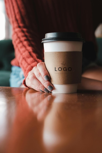 Een vrouw houdt een koffiekop vast met het logo erop.