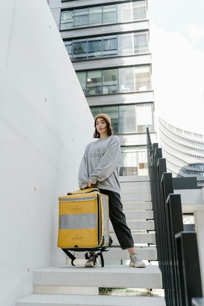 een vrouw in een grijze sweatshirt staat op een trap met een gele koffer