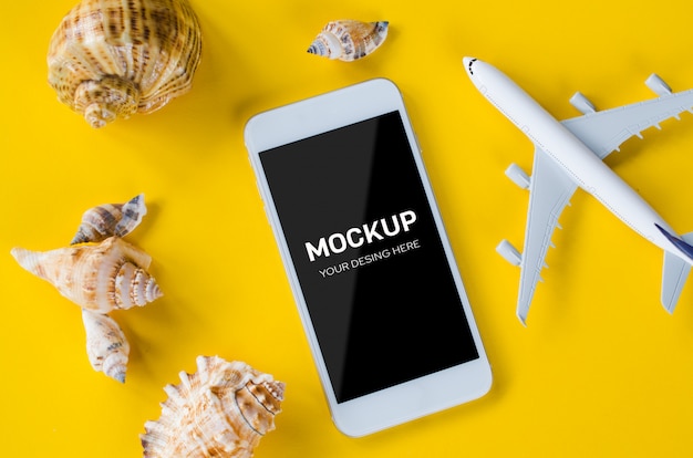 Empty screen smartphone, decorative airplane and seashells, template for app presentation.