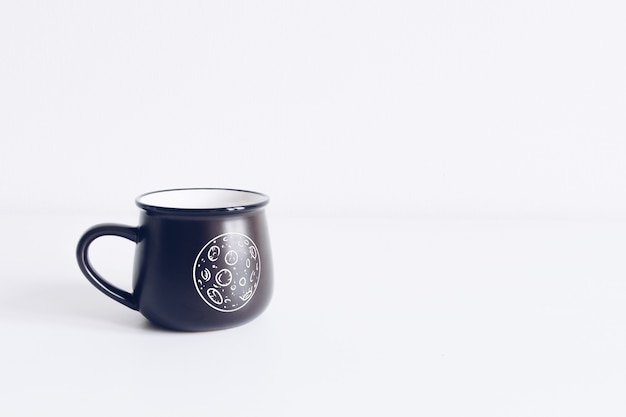 Enamel black mug on white table  mockup.