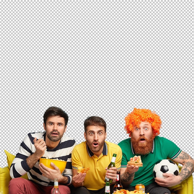 Excited three male friends watch sport tournament have bated breath during dangerous moment bite crisps popcorn and pizza sit on yellow sofa in living room Soccer fans with beer Football supporter