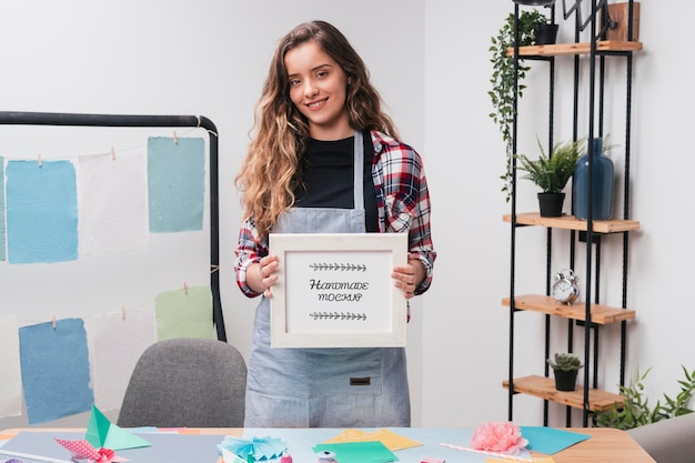 Female artist in the studio holding mock-up frame