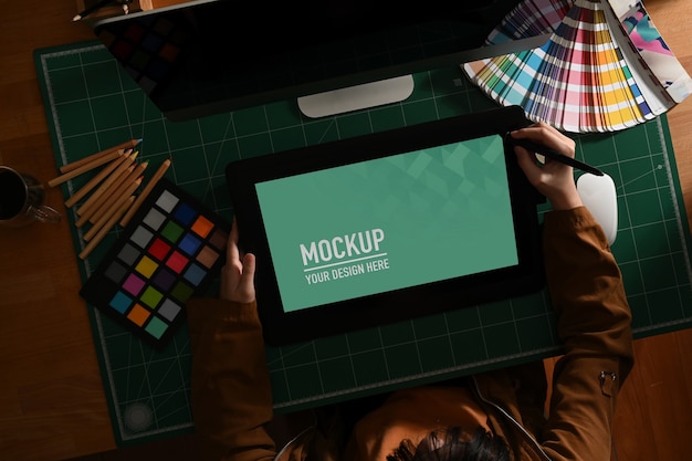 Female graphic designer working with mock up tablet and designer supplies on computer desk