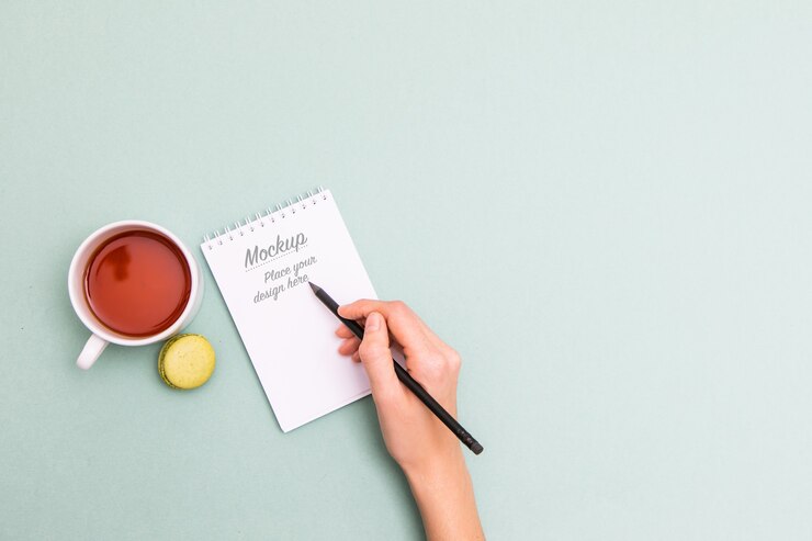 PSD female hand holding black pencil and writing in notebook mockup