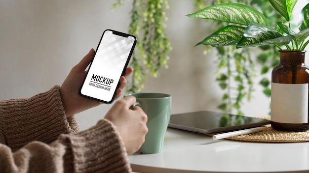 Female hand using smartphone mockup on coffee table