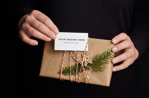 Female hands holding Christmas gift box with business card mockup