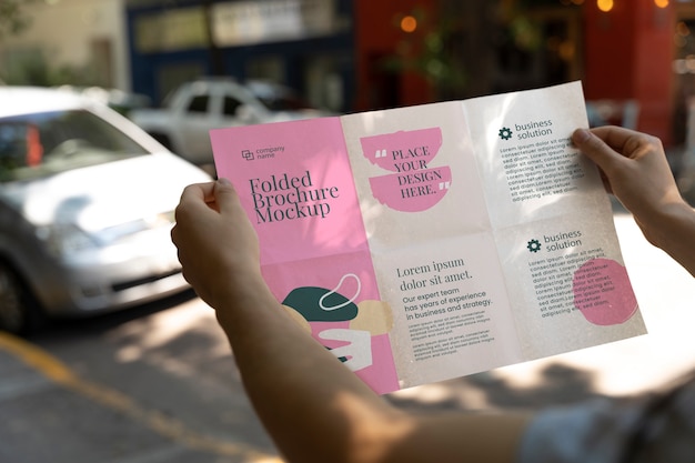 Mani femminili che tengono un modello di brochure a tre ante con forme astratte