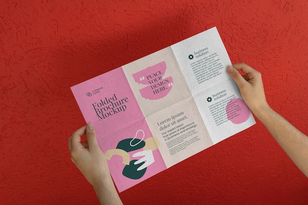PSD female hands holding trifold brochure mock-up with abstract shapes