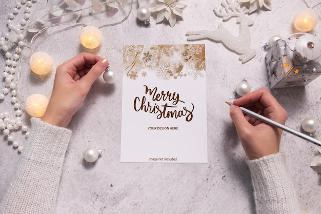 女性の手はクリスマスのポストカードやウィッシュリストを書きます。クリスマスの時期のお祝いの雰囲気