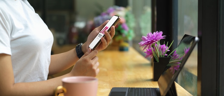 PSD female holding mockup smartphone while sitting at bar in cafe