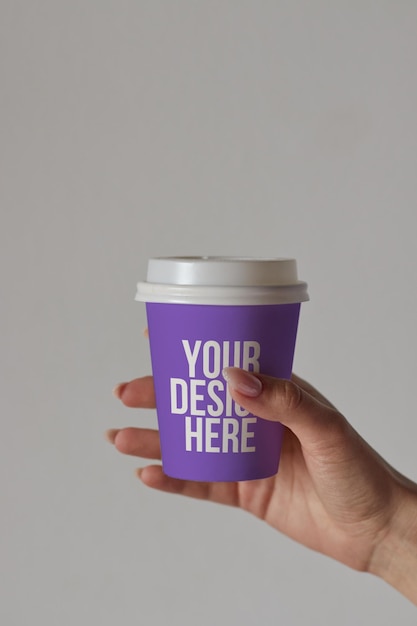 Fioletowa filiżanka kawy w ręku makieta niestandardowy projekt zmienny kolor zbliżenie