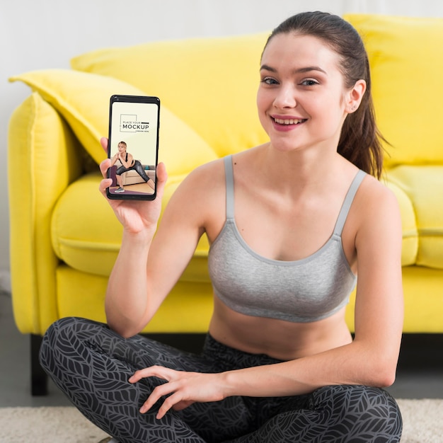 Fitness woman holding a mobile phone mock-up