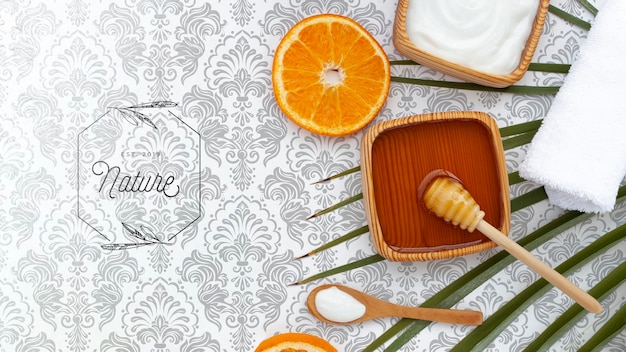 Flat lay of body butter and honey with orange slice