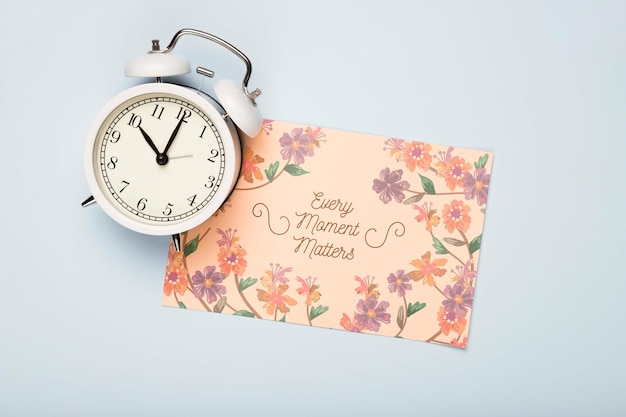 Flat lay of clock and floral card for spring