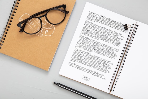 Flat lay of desk surface with notebooks and glasses