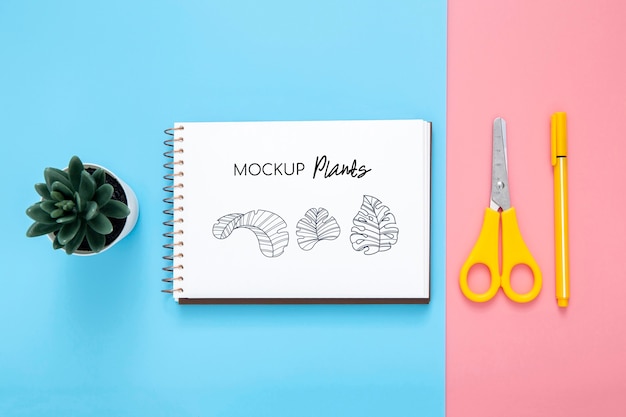 Flat lay of desk surface with notepad and scissors