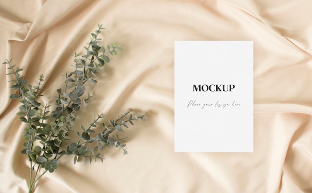 PSD flat lay mockup greeting card with eucalyptus on the nude fabric background