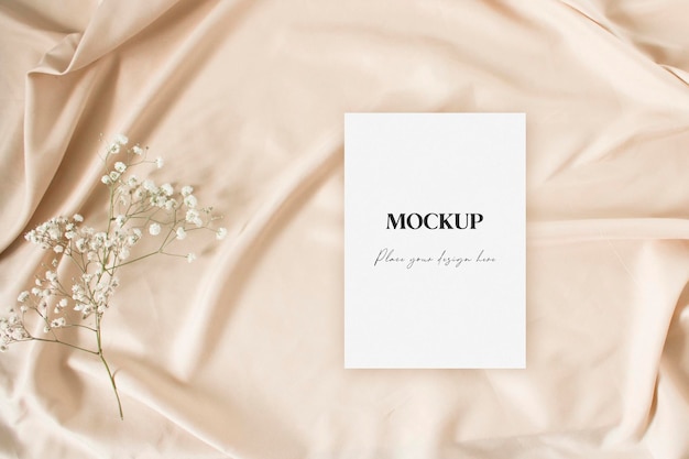 PSD flat lay mockup invitation with gypsophila on the nude fabric background