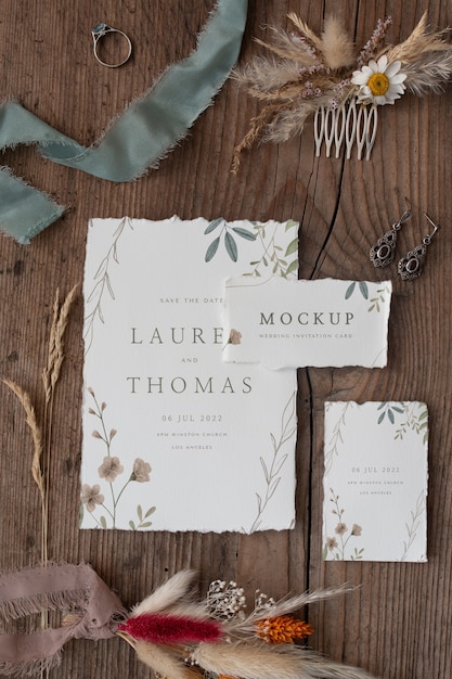 Flat lay of paper mock-up rustic wedding invitation with leaves and flowers