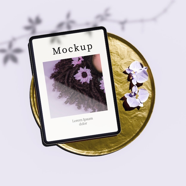 flat lay of tablet on golden tray with flowers