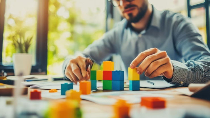 PSD focused businessman building colorful blocks on desk