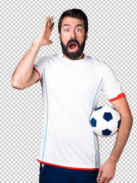 Football player holding a soccer ball making surprise gesture