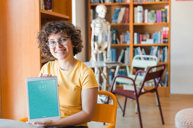 PSD friendly woman holding tablet mockup in library