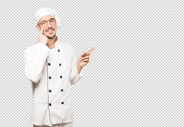 Friendly young chef making a gesture of being careful with his hand pointing at his eye