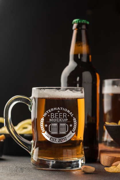 Front view of beer bottle and pint with assortment of snacks